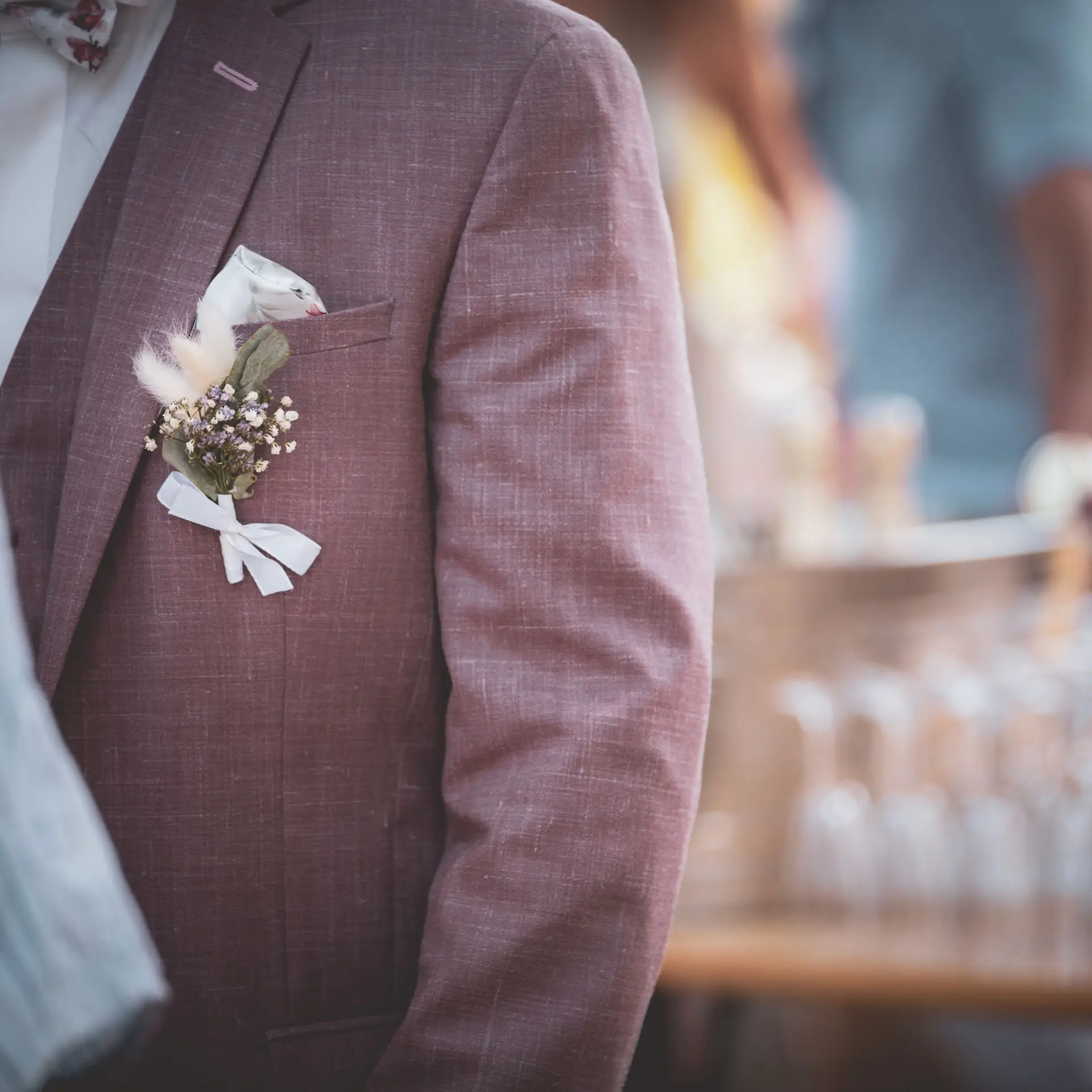 Détail d’un costume de mariage avec une boutonnière en fleurs séchées et ruban blanc, réalisée par Yello Event dans le Gard