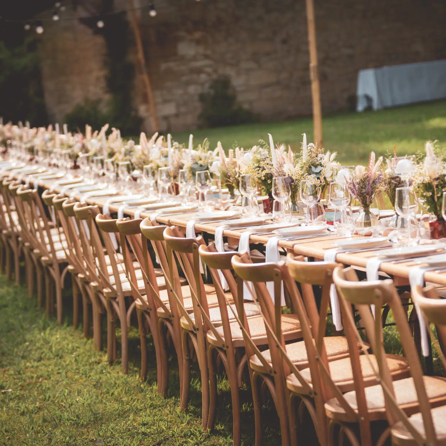 Table de mariage champêtre en plein air, décorée de fleurs sauvages et vaisselle raffinée par Yello Event dans le Gard