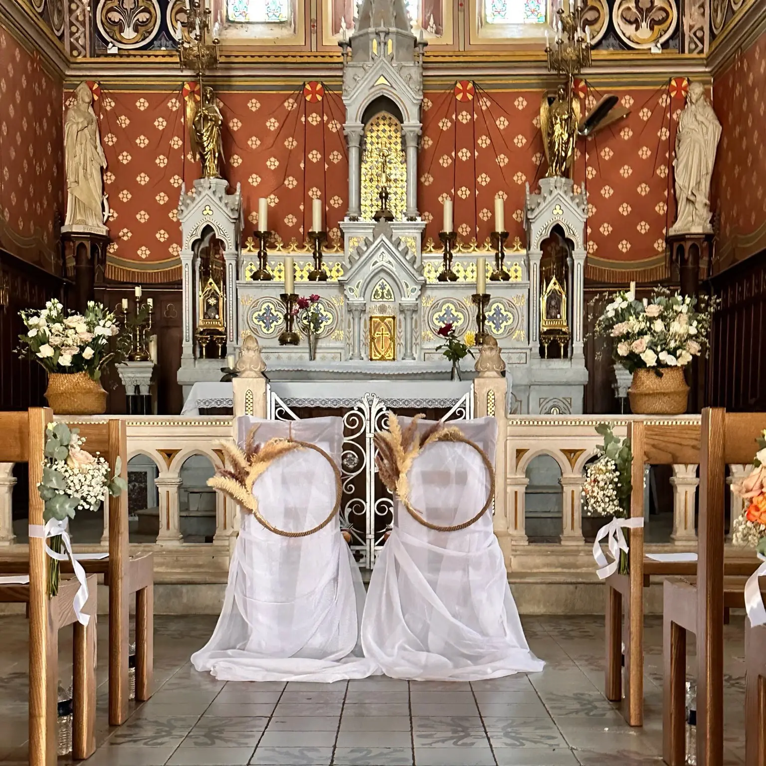 Décoration de cérémonie de mariage dans une église, chaises habillées de voiles blancs et couronnes de fleurs séchées devant l’autel)