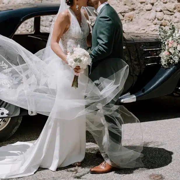 Mariés s’embrassant devant une voiture ancienne lors d’un mariage chic organisé dans le Gard par Yello Event