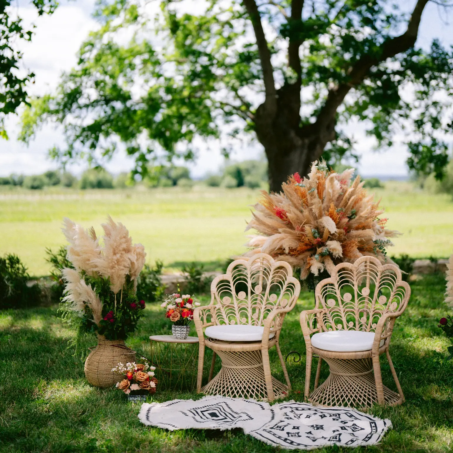 Coin lounge de mariage bohème chic signé YelloEvent, fauteuils en rotin et fleurs séchées dans un jardin du Sud da deux pas de Nîmes