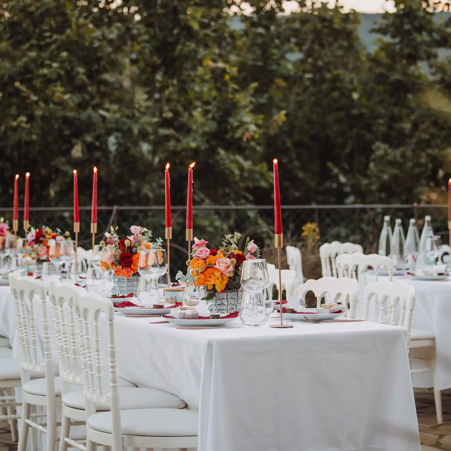 Tables de mariage élégantes dressées avec chandelles rouges et compositions florales colorées par YelloEvent & Co