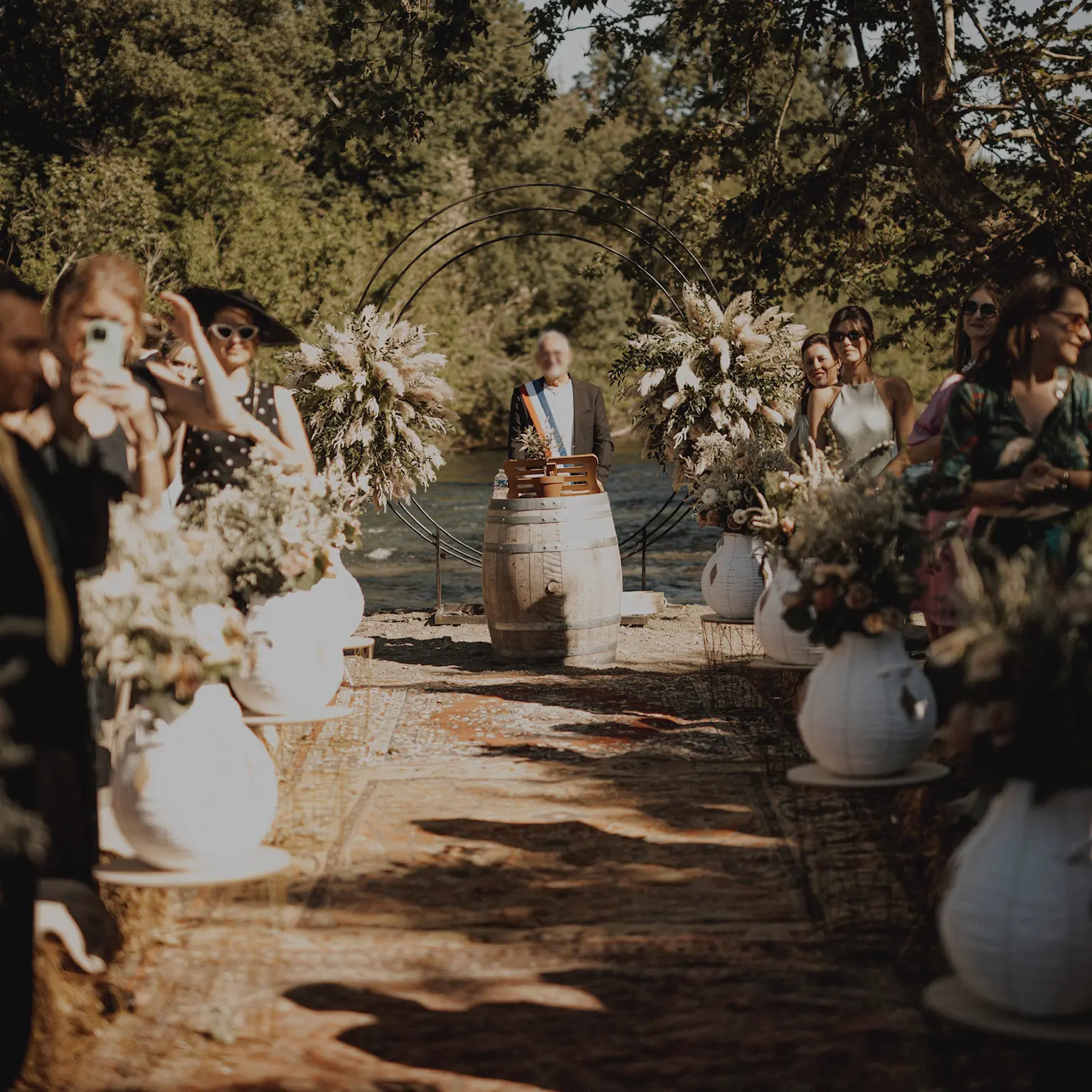 Cérémonie de mariage en plein air organisée par YelloEvent, arche florale et décoration bohème au bord de l’eau