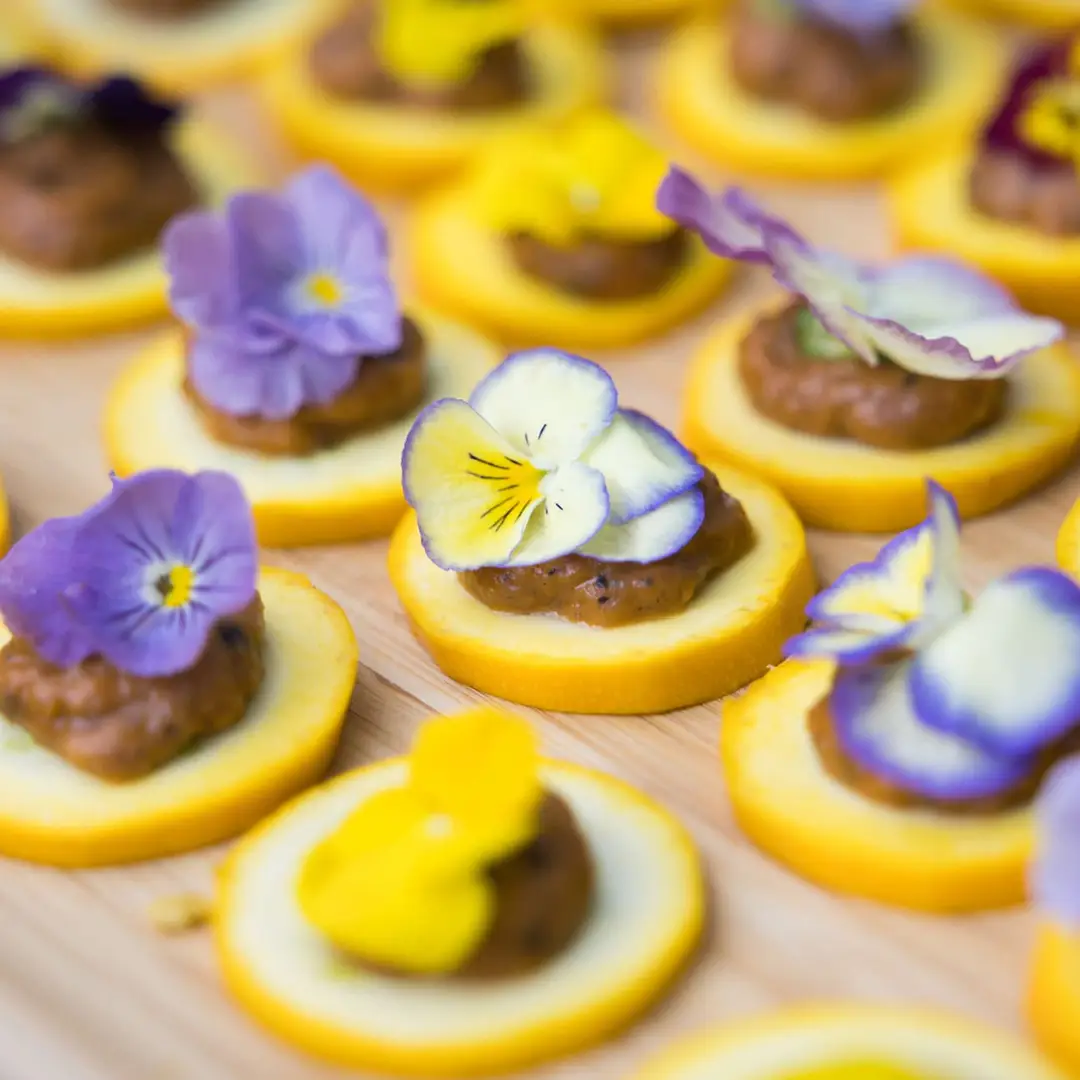 Canapés apéritifs sur base de sablés salés garnis de crème et de fleurs comestibles – traiteur événementiel