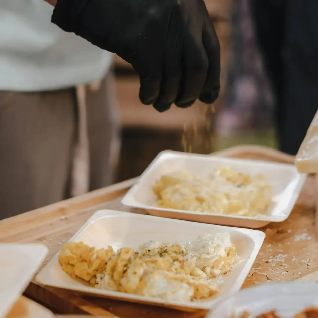 Dressage de pâtes fraîches avec fromage râpé par un chef ganté, lors d’un service traiteur Yello Event dans le Gard