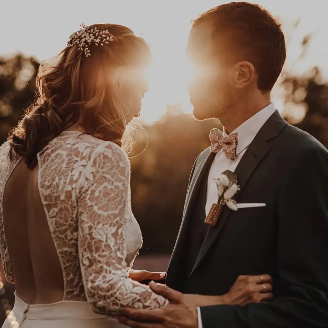 Mariés s’enlaçant au coucher du soleil avec lumière dorée entre leurs visages